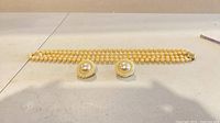 Necklace laid flat with both clip-on earrings positioned in front