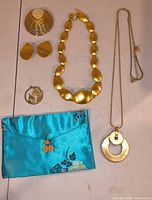 Full lot showing two necklaces, brooch, pendant, earrings, pouch