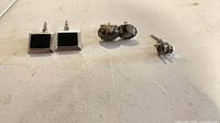 Full view of both cufflink pairs and tie tack on surface