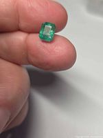 Emerald held between fingers showing size and clarity