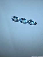 Three oval faceted blue topaz gemstones on white background