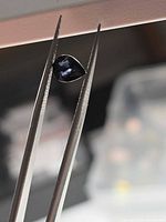 Pear-cut deep purple spinel held in tweezers