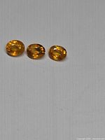 Three oval mandarin orange sapphires on neutral background