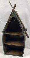 Full view of boat-shaped wooden shelf showing three tiers and oar-like side details