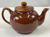 Side view of brown glazed teapot with lid