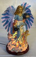 Front view of illuminated resin angel figurine showing cherub and color-changing base