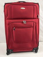 Full front view of red Samsonite suitcase showing exterior pockets and wheels