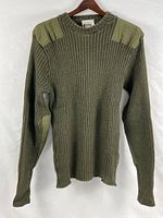 Front view of olive wool commando sweater on hanger displaying rib knit, crew neck, shoulder patches