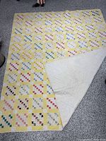 Full view of quilt front showing patchwork design and yellow sashing