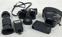 Full kit layout showing camera with 50 mm lens, Vivitar 70-210 mm lens, SB-E flash, and two Nikon leather cases