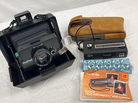 Overall view of Polaroid ProPack camera in case, Kodak Tele-Instamatic 608 camera, flash bar, booklet and pouch