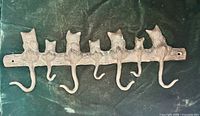 Front view of cast iron cat rack showing six tail hooks and mounting holes