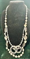 Full view of double-strand clear and white lucite bead necklace on display bust
