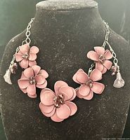 Front view of mauve floral statement necklace with dangling earrings displayed