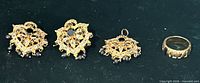 Set showing earrings, pendant, ring on dark background