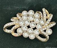 Front view of gold-tone floral brooch with faux pearl cluster and rhinestones