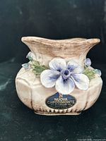 Front view showing applied blue flower, label and overall shape