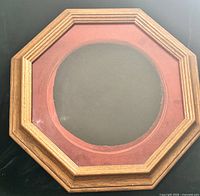 Front view of octagon wood frame showing round opening and red fabric lining