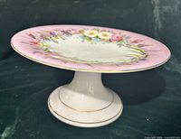 Angled view of porcelain compote showing pink rim, floral decoration, pedestal base