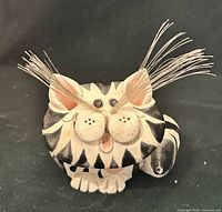 Front view of striped ceramic cat figurine showing face, whiskers, painted details