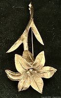 Front view of gold-tone floral brooch showing flower and leaves
