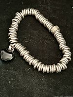Full view of bracelet laid flat showing coil construction and charm