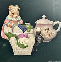 Group shot showing pink cherub teapot alongside other items for scale