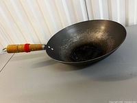 Top view of carbon steel wok showing interior seasoning and wooden handle with red rings