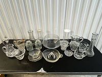 All sixteen clear glass items arranged on table