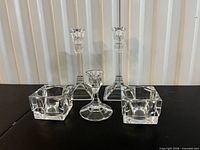 Group of five clear glass candleholders: two tall column, one pedestal, two cube