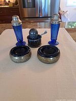 Full group showing two tall shakers, two open salts, pierced holder, shaker top, spoon