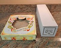 Front view of boxed ceramic shortbread pan alongside boxed rolling pin