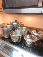 All pots, lids and insert baskets grouped on stovetop