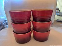 Front view of six stacked Le Creuset red ombre ramekins