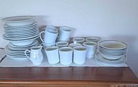 Full set stacked on sideboard showing plates, bowls, mugs, cups, creamer, sugar bowl