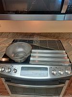 Group shot of all items on stovetop: large sieve, two wire racks, perforated baguette pan