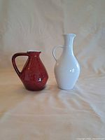 Red and white ceramic pitchers side by side front view