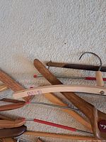 Group of assorted wooden hangers showing red-sleeved pant bars and metal hooks