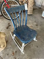 Front angled view of blue and white wood rocking chair showing arrow back design and paint wear