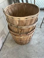 Stack of four wood bushel baskets against wall