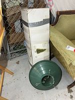 Boxed pre-lit tree alongside green plastic stand