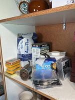 Shelf with boxed Aqua-Pure filter, deck grommet, kettle, pencil sharpener, blank CDs, playing cards visible