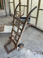 Full view of vertical wooden hand truck with metal handles and wheels