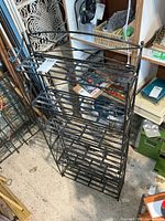 Front view of black metal folding bookshelf showing slatted shelves