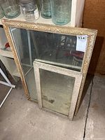 Two wood framed mirrors leaning against shelf