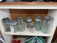 Seven glass sealer jars on shelf showing overall lot
