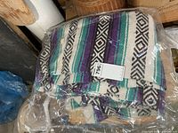 Throw folded in plastic bag showing striped pattern and auction sticker