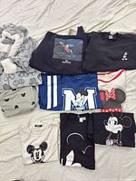 Group shot displaying all 9 clothing pieces including onesie, sweatshirts and T-shirts