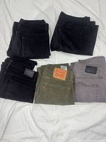 Five folded pairs of jeans—three black, one green Levi’s, one grey Lucky Brand
