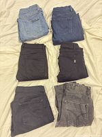 Six folded pairs of jeans showing back pockets and colour variety